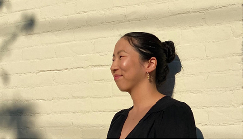 Cindy Ok standing against a brick wall smiling