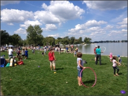 People on the grass near the lake with hula hoops