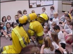 Firefighter teaching Stop, Drop, and Roll to a group of children